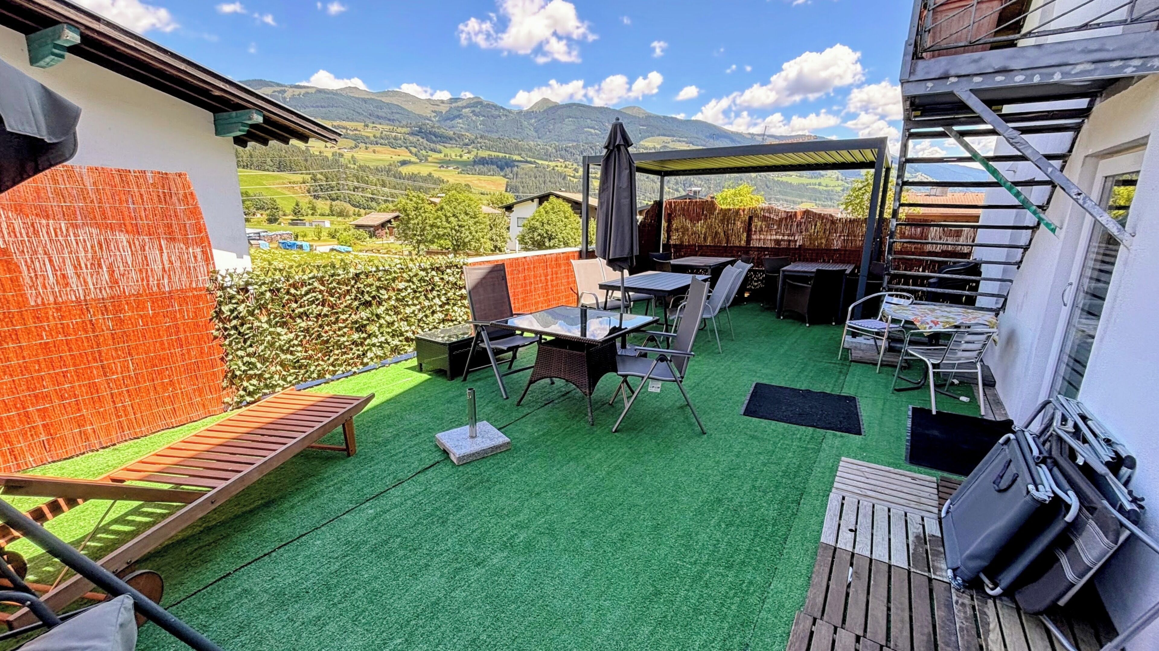 Terraço no telhado com vista para montanhas, área para churrasco e mesas ao ar livre.