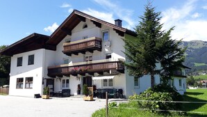 A two-story building with a balcony, outdoor seating, and a mountain view.