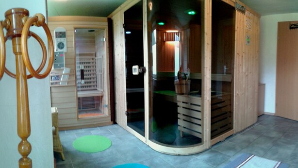 A room with a sauna, a wooden cabinet, and a green mat on the floor.