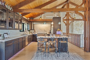 A spacious kitchen with wooden beams, a marble backsplash, and a central island with chairs.