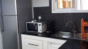 Cozinha moderna com geladeira de aço inoxidável, micro-ondas, fogão a gás e pia.