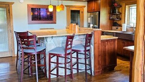Una cocina con techo de madera, barra y mesa de comedor con sillas.