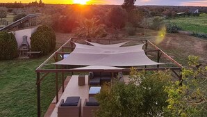 Área de pátio com mobiliário externo e vista para o pôr do sol.