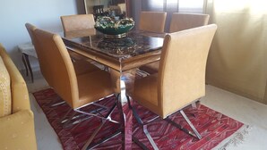 A dining table with a green bowl centerpiece, surrounded by six brown chairs. - Very well equipped apartment, 2 bedrooms, living room, guarded parking (EL AOUINA)