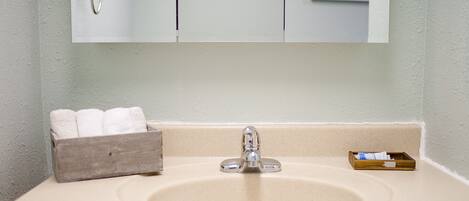 A bathroom sink with a mirror above it, a towel rack, and a small wooden box with a tissue box.
