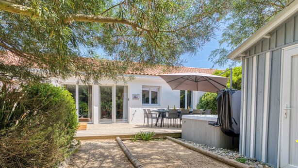 Un patio con mobiliario exterior, un jacuzzi y una zona cubierta con sombrilla.