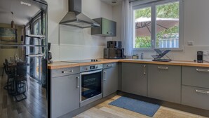Una cocina moderna con horno empotrado, refrigerador de acero inoxidable y ventana con vista a follaje.