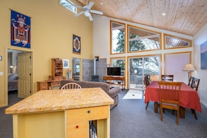 A spacious living room with a fireplace, a television, and a dining area with a red tablecloth.