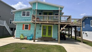 A two-story house with a balcony, a green door, and a welcome sign.