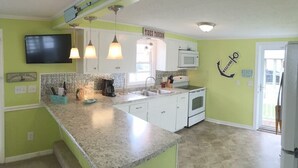A kitchen with a granite countertop, white cabinets, a microwave, a coffee maker, and a sign that reads "TIDES TAVERN".