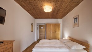 A bedroom with a wooden ceiling, a bed with white bedding, wooden cabinets, and a framed picture on the wall. - Sunny apartment in an ideal location to Lake Kaltern, historic village (Kaltern)