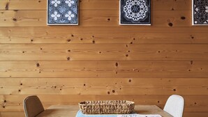 A wooden-paneled wall with three framed tiles, a wooden table with two chairs, and a woven basket on the table. - Sunny apartment in an ideal location to Lake Kaltern, historic village (Kaltern)