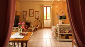 Un salon chaleureux avec un plancher en bois, une table à manger avec un set de table, un vase de fleurs et une chaise.