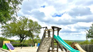 A playground with a slide, swings, and a climbing structure. - Hill Country Getaway with great views (Mountain Home)