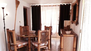 Un coin repas comprenant une table ronde, quatre chaises, une petite table d’appoint et un miroir accroché au mur.
