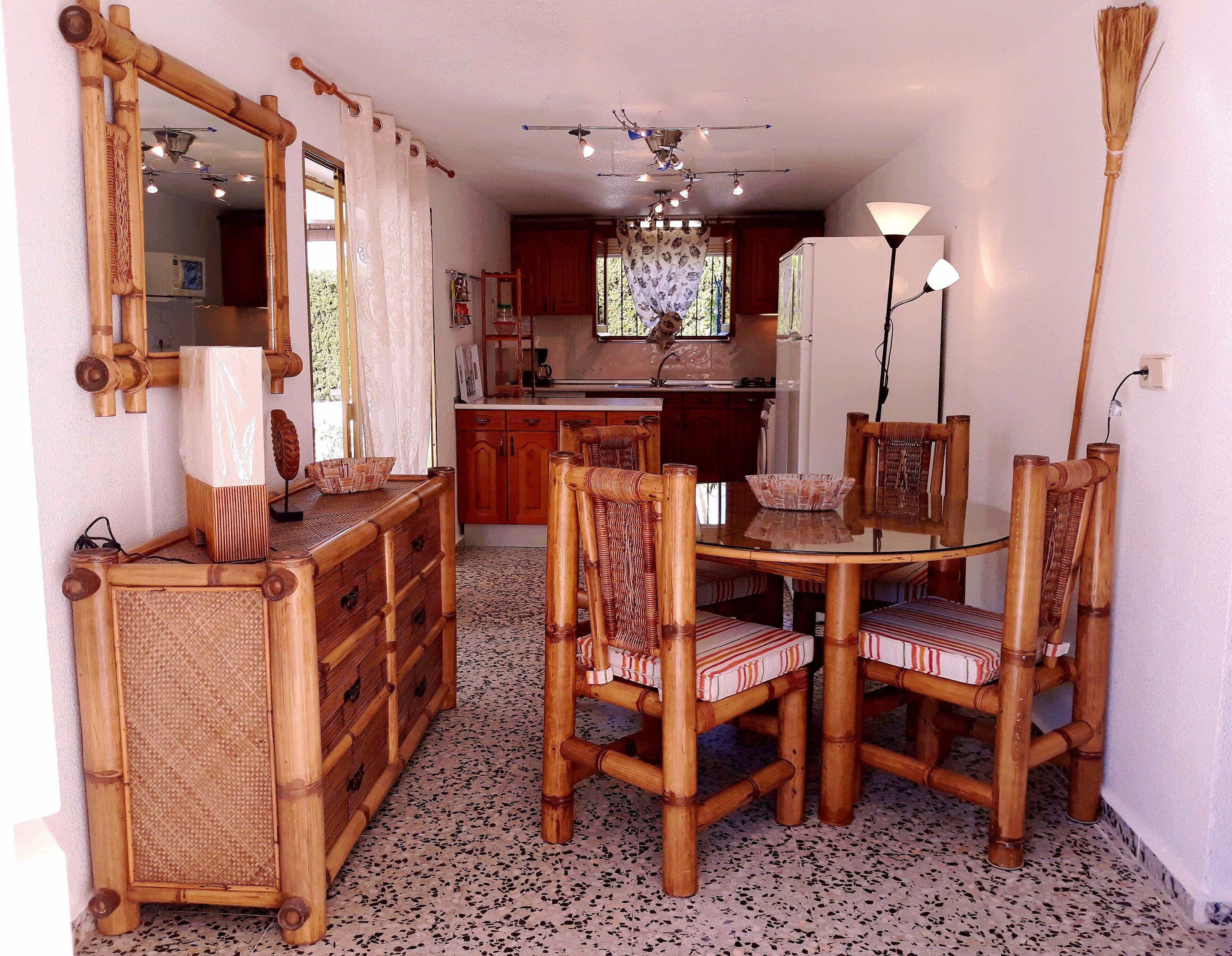 A dining area with a round table and four chairs, a wooden cabinet, a mirror, and a ceiling fan.