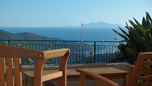 A wooden bench and table on a balcony overlooking a coastal view with mountains in the distance. - LARGE VILLA - 4 **** - HEATED SWIMMING POOL, 180° SEA VIEW - AIR CONDITIONED 
 (Sisco)