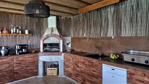 A rustic kitchen with a brick oven, wooden cabinetry, and a hanging light fixture. - LARGE VILLA - 4 **** - HEATED SWIMMING POOL, 180° SEA VIEW - AIR CONDITIONED 
 (Sisco)