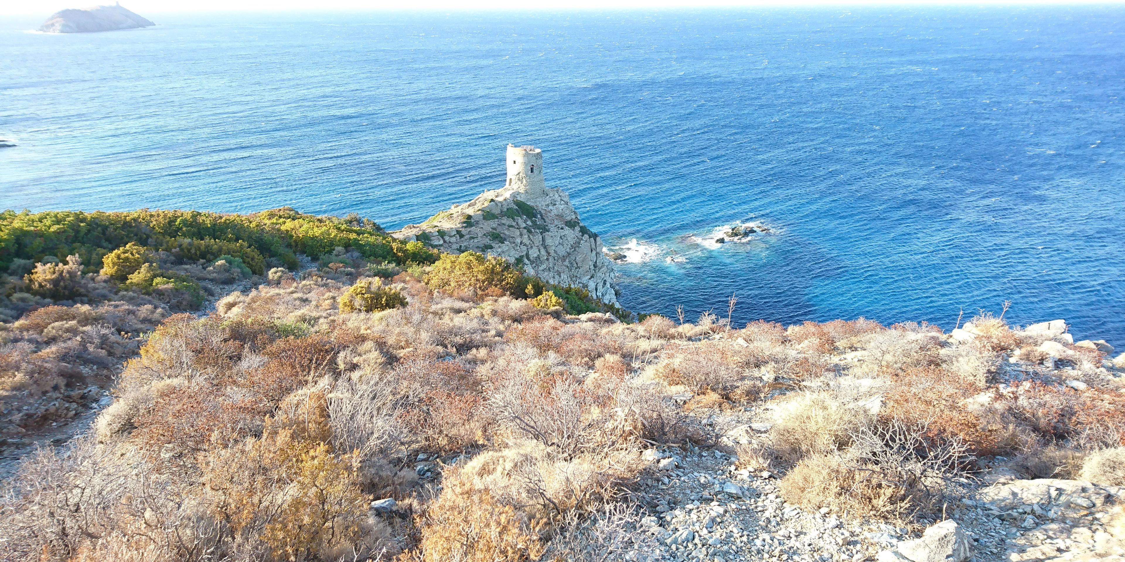 A coastal landscape with a rocky outcrop and a lighthouse.