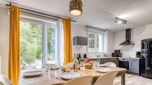 Ett modernt kök med matplats, stora fönster och utsikt över grönområden.