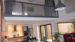 A modern apartment with a kitchen, dining area, and a red sofa.