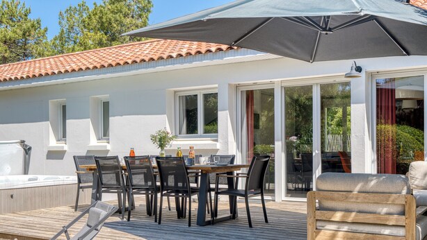 A covered outdoor dining area with a table and chairs, a wooden deck, and a poolside lounge.
