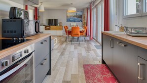 A modern kitchen with a microwave, stove, and dining area with chairs and a table.