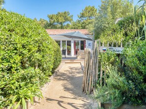 A pathway leading to a building with a red-tiled roof, a covered outdoor seating area, and a sign indicating the name 'Russie.' - Villa Russie - Domaine Le Sherwood (Notre-Dame-De-Monts)