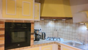 Una cocina con estufa negra, cafetera y pileta.