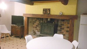 Una habitación con chimenea, televisión y una mesa de comedor con sillas.