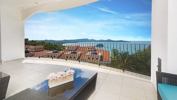 Ein Balkon mit Blick auf das Meer und die Berge, ausgestattet mit einem Tisch und Stühlen.