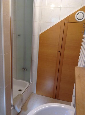 Un baño con cabina de ducha de vidrio, un mueble de madera y una bañera.