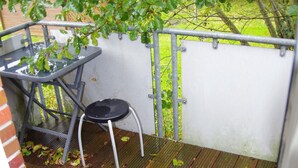 A small outdoor balcony with a wooden floor, a metal chair, and a table. - Apartment "Cockle" for 2P, at the North Sea between Dornumersiel and Bensersiel (Dornum)