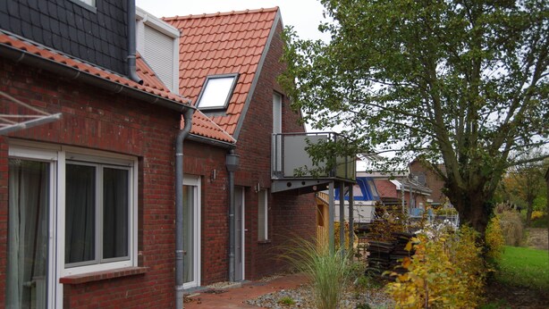 A residential building with a red brick facade, a sloped roof, and a visible window. - Apartment "Cockle" for 2P, at the North Sea between Dornumersiel and Bensersiel (Dornum)