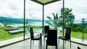 A modern room with a glass wall offering a view of a lake and mountains. - 2B/1B CORNER CONDO SUITE with VIEWS (Tilaran)