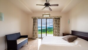 A bedroom with a bed, a chair, a ceiling fan, and a view of the outdoors. - 2B/1B CORNER CONDO SUITE with VIEWS (Tilaran)