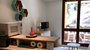 Eine Küche mit Mikrowelle, Herd und einer Holzausstattung. Ein Fernseher steht auf einem Schrank und ein Fenster bietet Blick ins Freie.