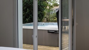 Ett rum med ett stort fönster med utsikt över en bubbelpool och en träterrass.