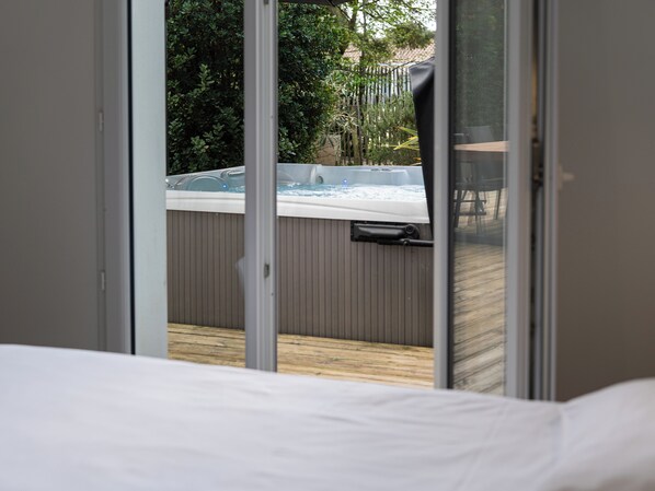 A room with a large window overlooking a hot tub and a wooden deck.