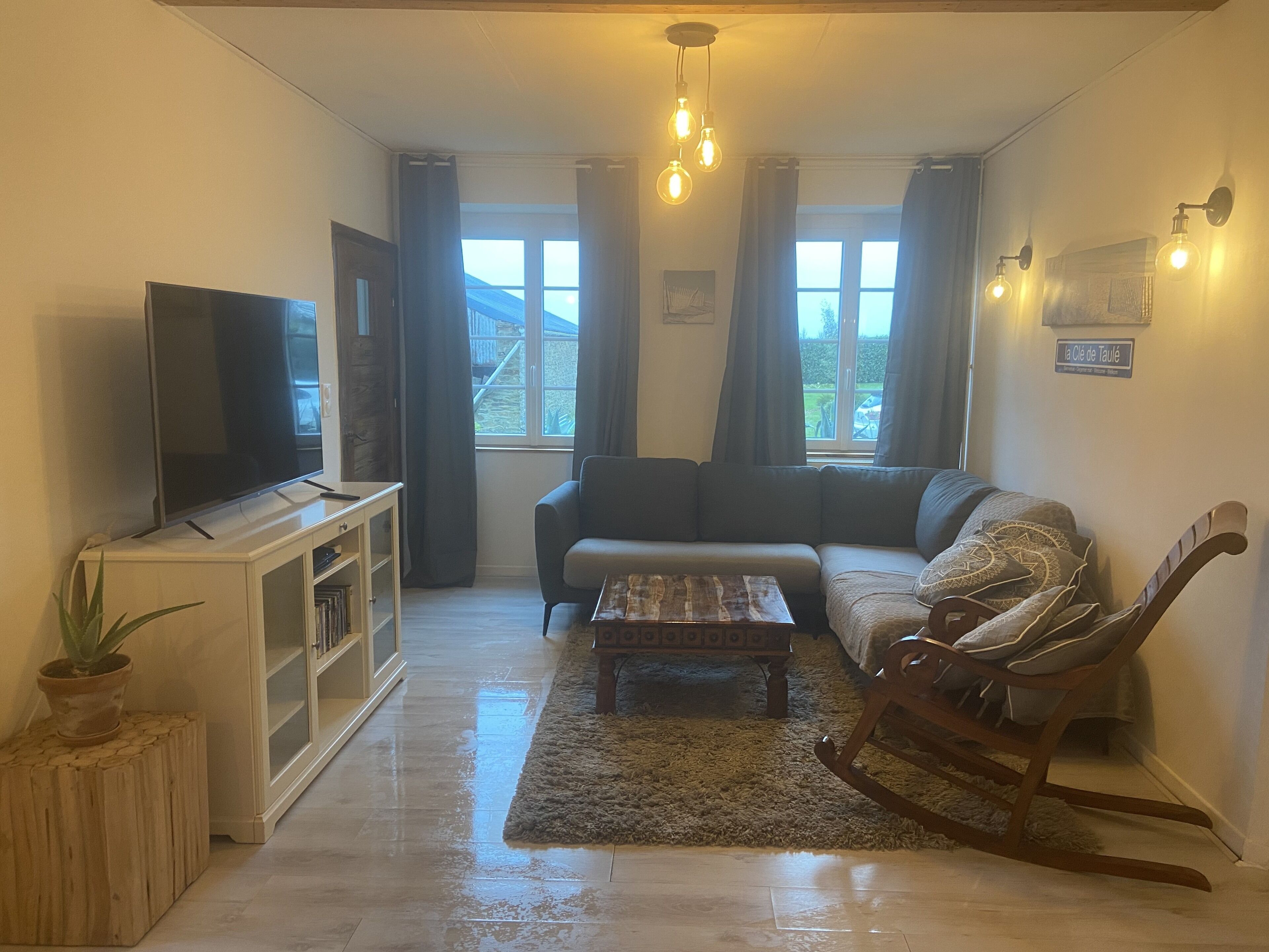 A living room with a flat-screen TV, a sofa, a rocking chair, and a coffee table.