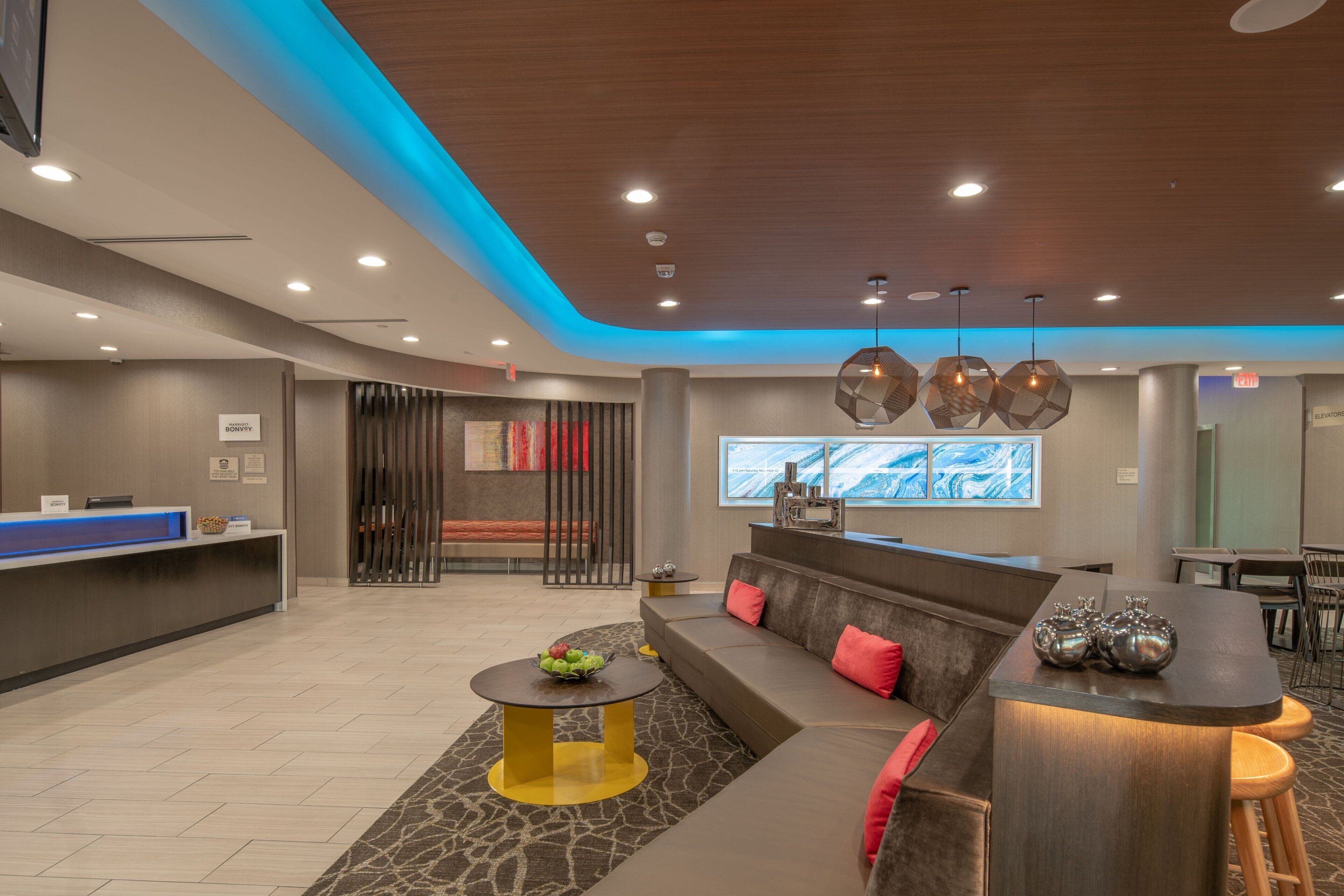 A modern lobby with a reception desk, seating area, and a large window with a cityscape view.