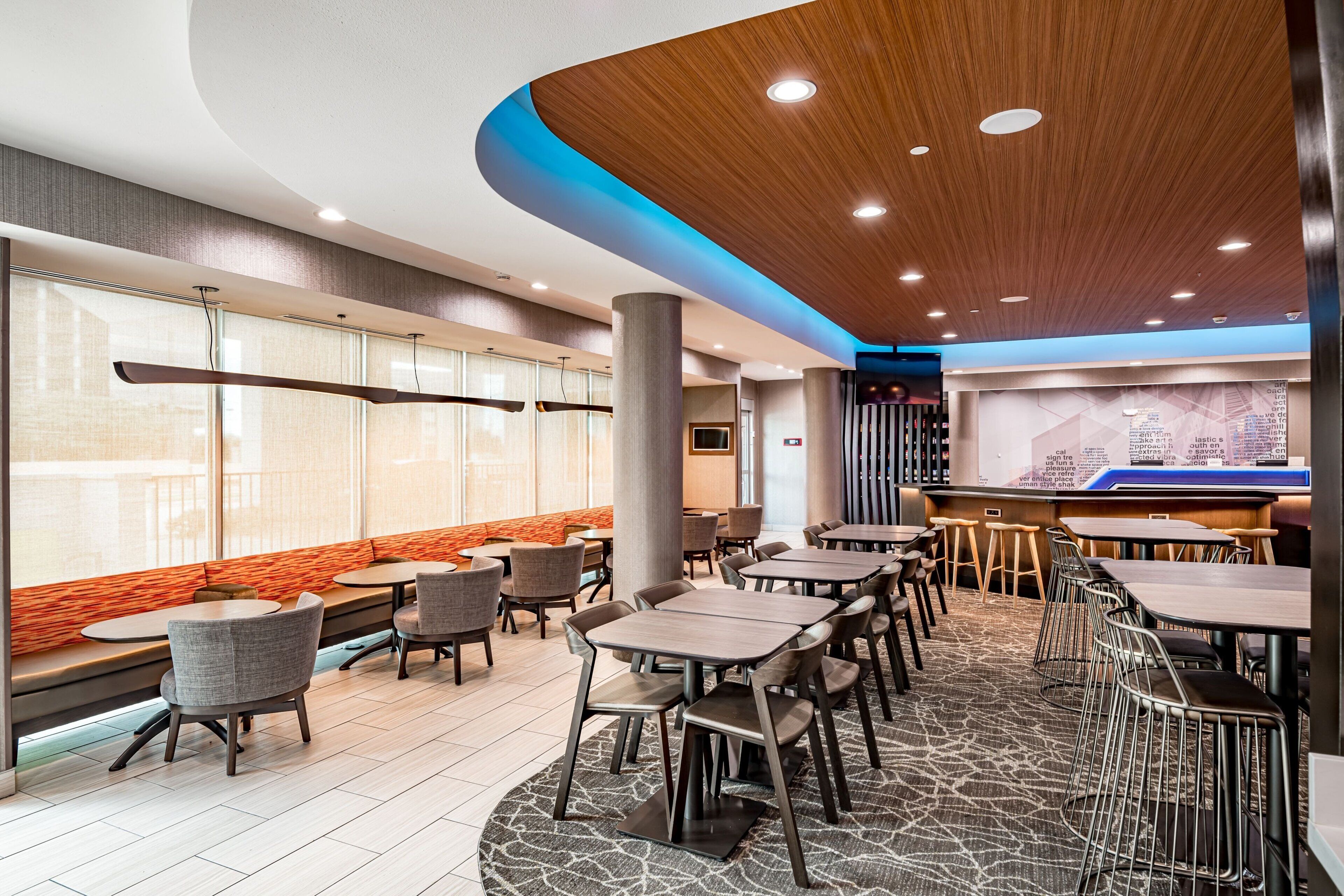 A modern restaurant with high tables and chairs, a bar area, and a large window with a view.