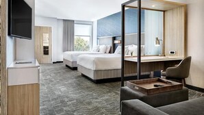 Une chambre d’hôtel avec deux lits, un bureau, une télévision et une grande fenêtre.