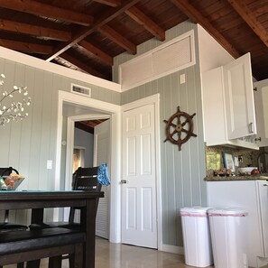 Una cocina con armarios blancos, techo de madera y decoración de timón.