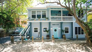 A two-story building with a balcony, a front door, and a staircase leading to the upper level. - Boat House Beach Suite by Island House Vacation Rentals (West Bay)