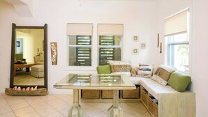 A modern living room with a glass coffee table, a sofa with cushions, and a large mirror. - Boat House Beach Suite by Island House Vacation Rentals (West Bay)