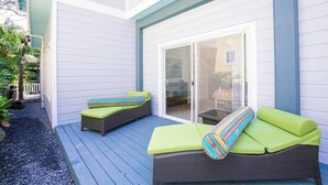 A covered patio with two wicker lounge chairs and a glass sliding door. - Boat House Beach Suite by Island House Vacation Rentals (West Bay)