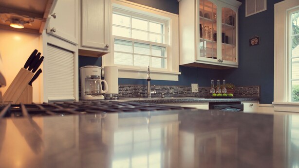 Una cucina dal design moderno, con un piano di lavoro in acciaio inossidabile, mobili bianchi e una finestra che offre luce naturale.
