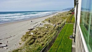 Vista sulla spiaggia con una zona verde e un edificio con facciata in vetro.