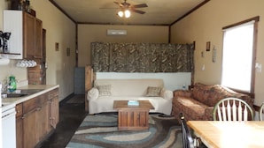 A compact living space with a kitchenette, a sofa, a dining table, and a ceiling fan. - Spacious Norfork Lake View Bunkhouse, Resort Amenities, Family/Fishermen/Pets (Gamaliel)